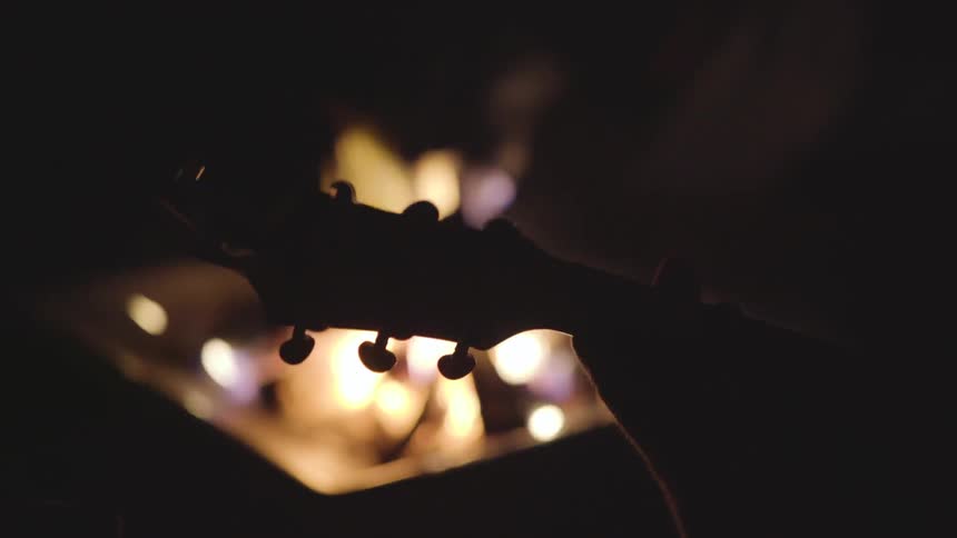 Someone place a guitar in front of a fire in the dark
