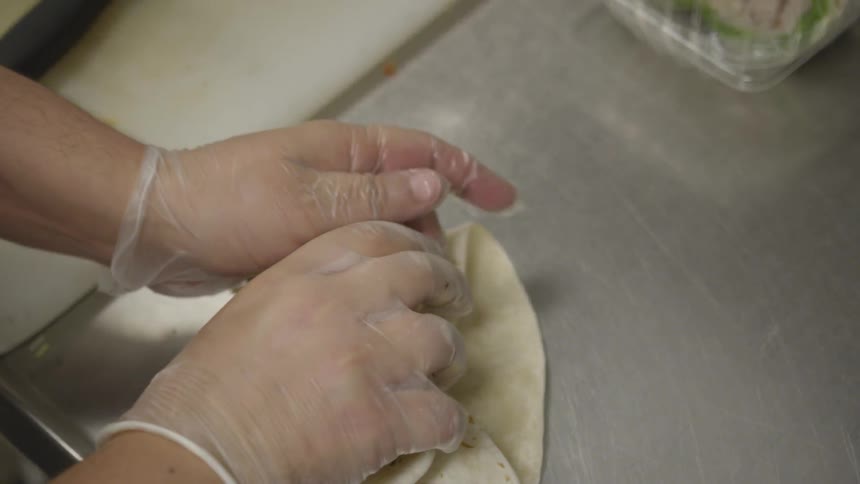 A person folding up a burrito