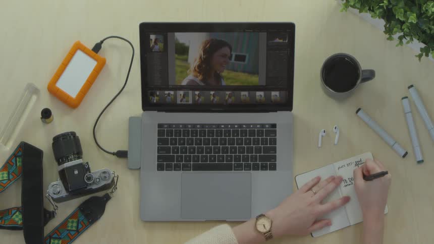 A person writing in a notebook next to a computer