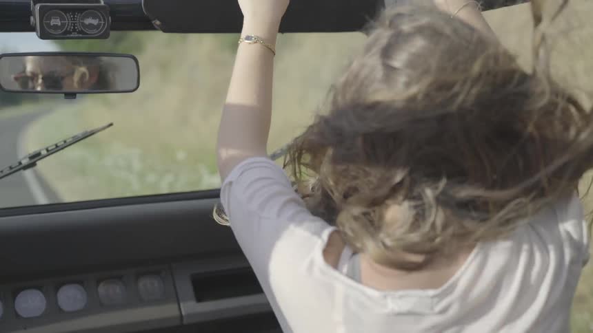 Woman dances while riding in convertible