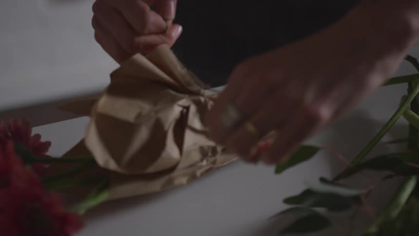 A woman wraps and ties some flowers together