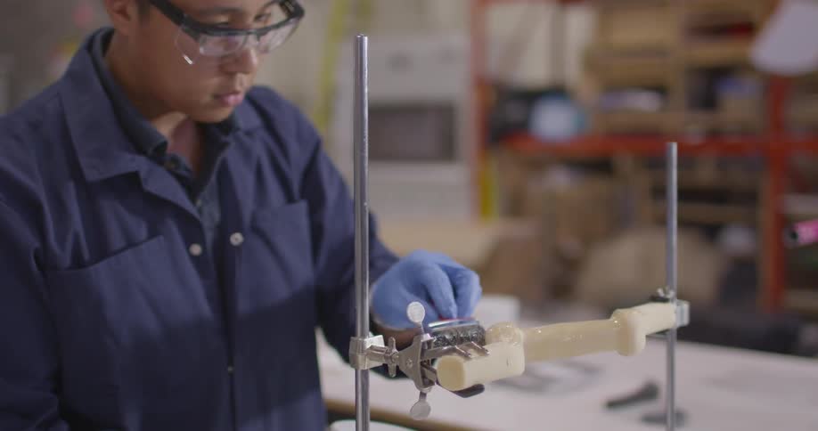 Worker uses a brush to cover a plastic piece with laquer on a warehouse