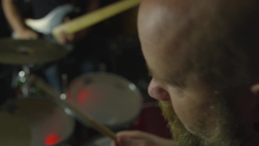 A ,am with a beard plays the drums