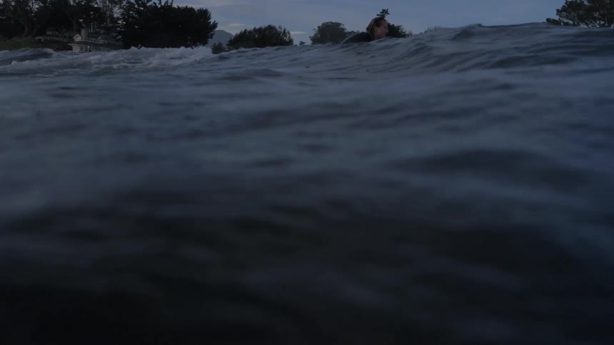 A surfer swimming on his surfboard