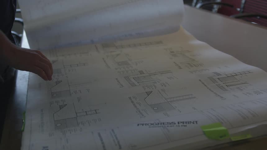 A person looking at some blueprints