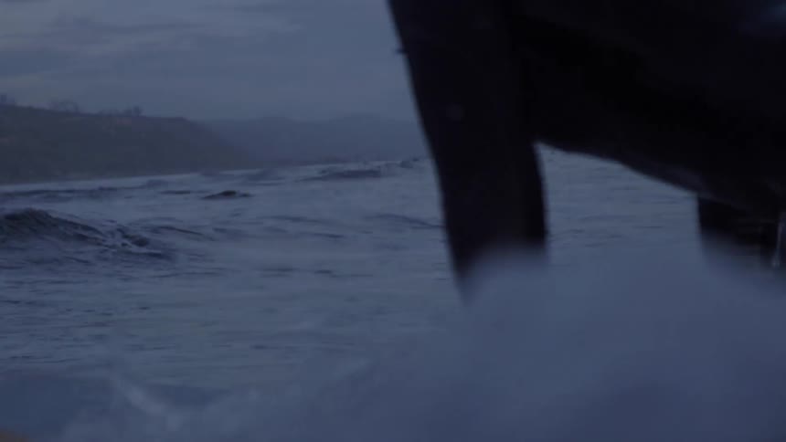 A woman on a surfboard paddles toward the shore