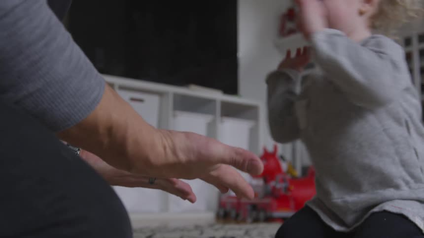 Father plays with laughing toddler on floor