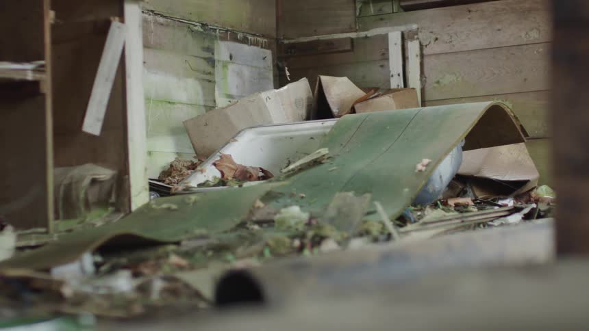 Debris and rubble cover the abandoned building