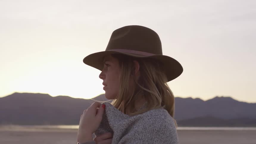 Woman is brown hat and a sweater looks at the mountains in awe