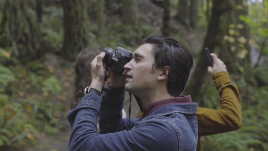 Men are taking pictures in the forest together