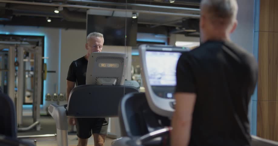 A man steps onto a treadmill and starts running