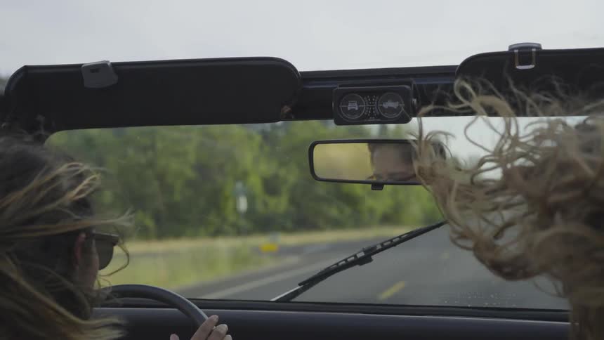 Two women driving in convertible and talking