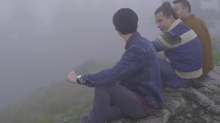 Men sit on a rock and chat in the fog