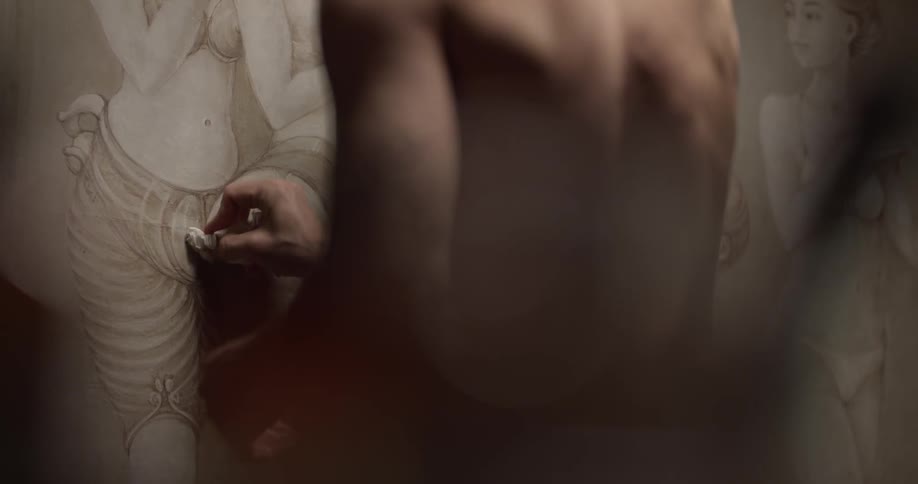 A man rubs a painted canvas with a cloth