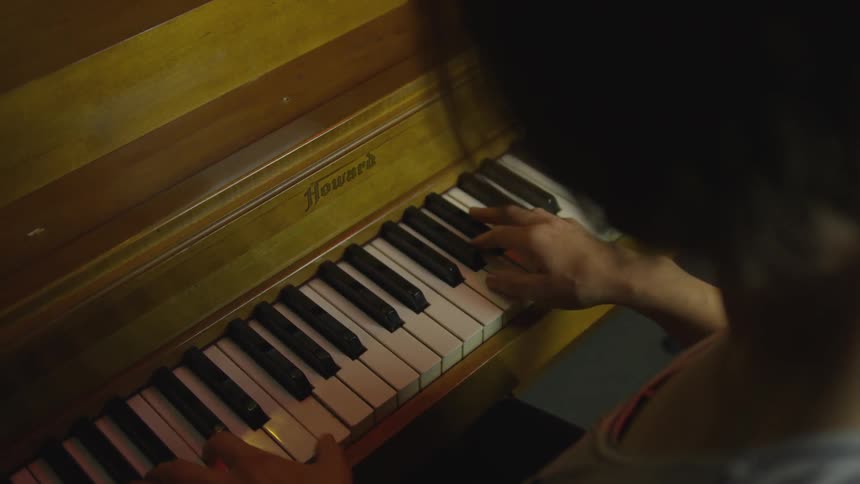 Person plays upright piano
