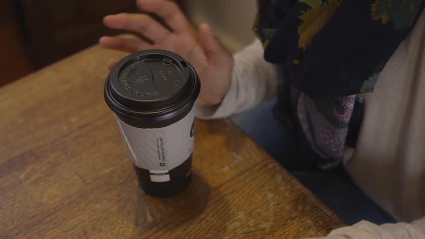 A woman gestures her hands while talking at a cafe table