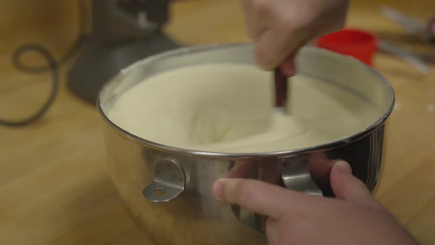 A person stirs batter in a mixing bowl