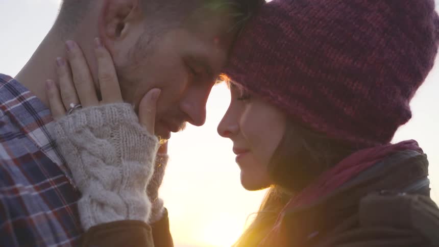 A man and a woman stand outside with their foreheads pressed together