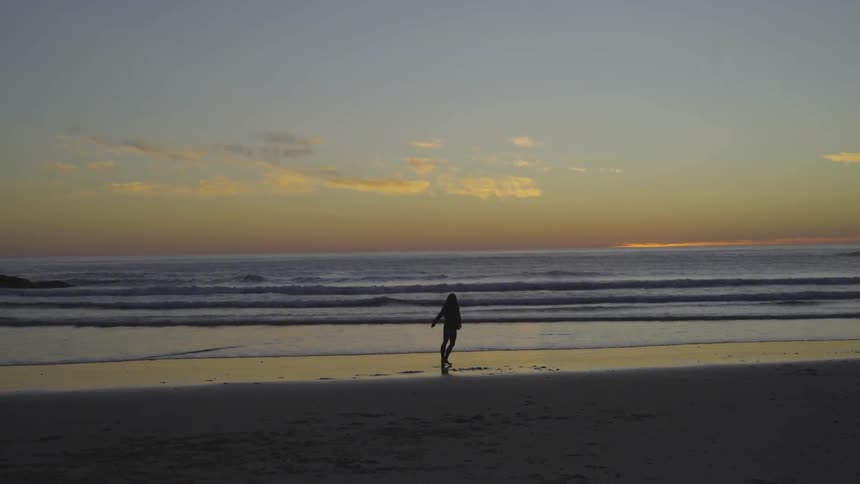 Woman dances on the beach at sunset
