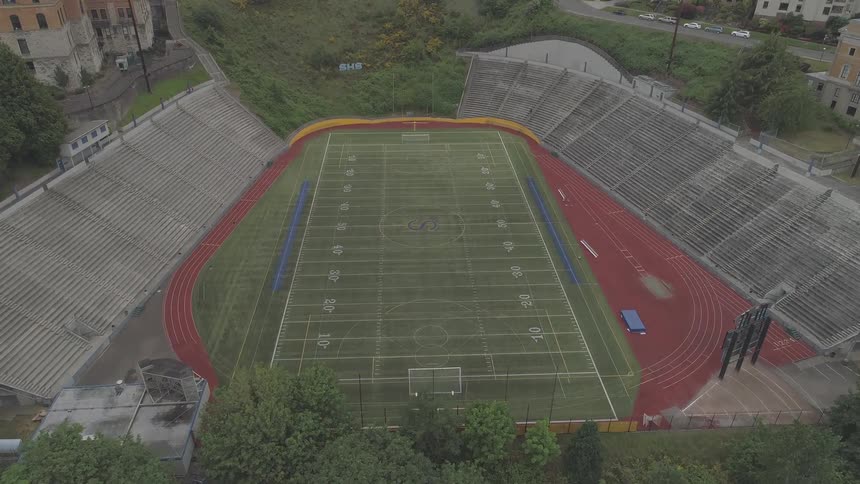 A freshly painted football stadium sits empty amongst the trees
