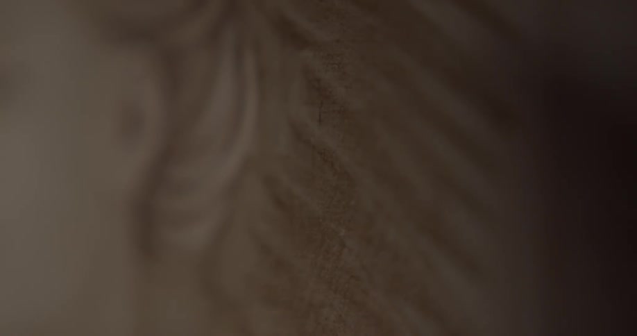 A paintbrush fans and strokes brown paint on a canvas