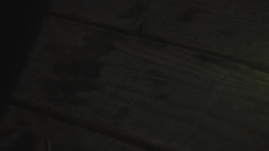 A person lights there way across a wooden floor with a flashlight