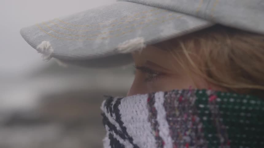 Girl wearing a hat and a scarf on a beach