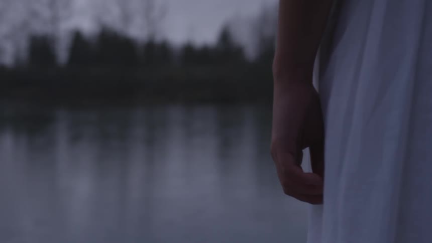 Woman stands on shore near water