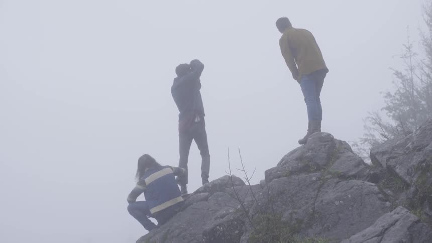 Hikers stand on a boulder on a foggy day