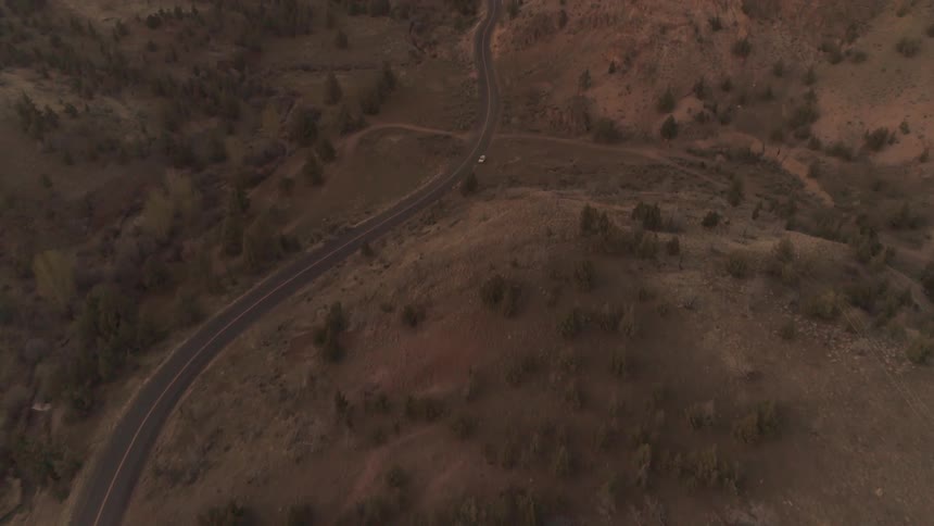 A road winding through hills that have brown grass on them
