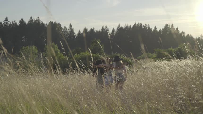 Three women walk together though the tall grass
