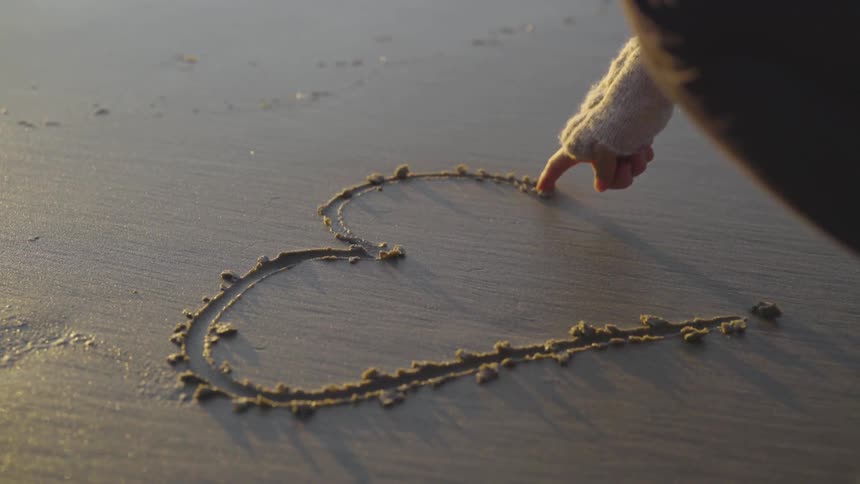 A person drawing in the sand at a beach