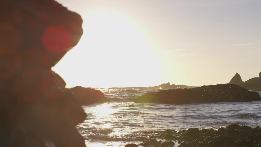 Sun rises across the sea and rocks