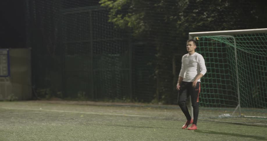 A man is walking towards the goal while playing soccer
