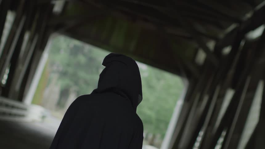 A person wearing a hooded jacket walks across the bridge