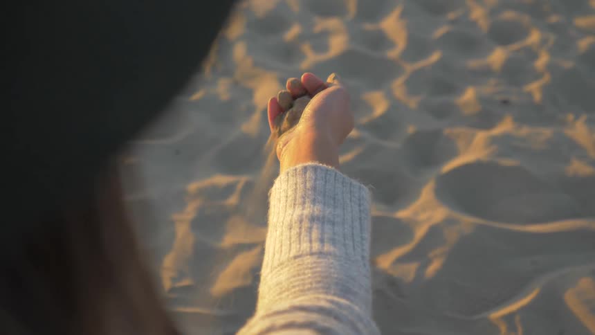 A woman picking up sand at the beach