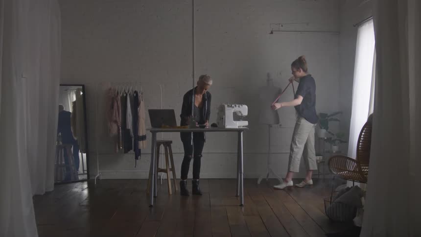 A woman uses a mannequin to measure