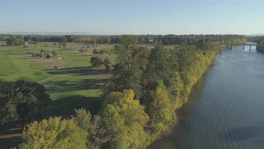 The camera rises over a river and grassy area