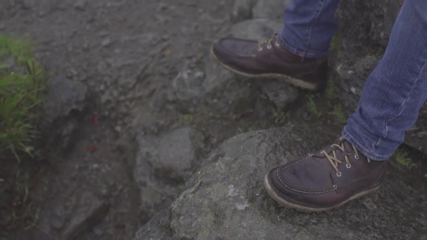 A person wearing boots standing on rocks