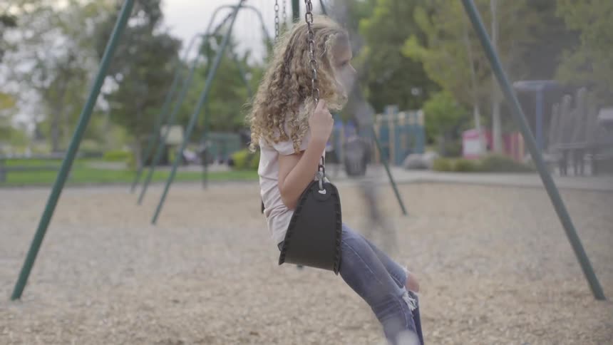 Little girl on a swing at a park
