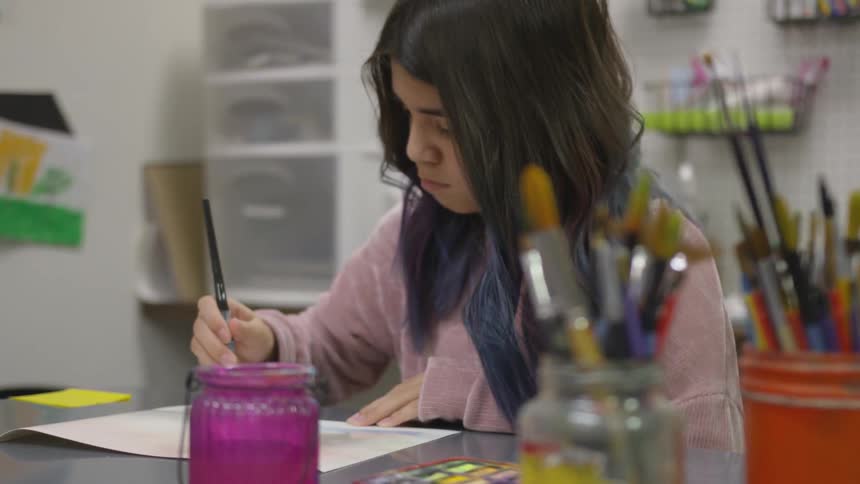 Child painting on a paper in a craft room