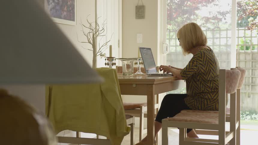 A woman sitting at a table typing on a laptop