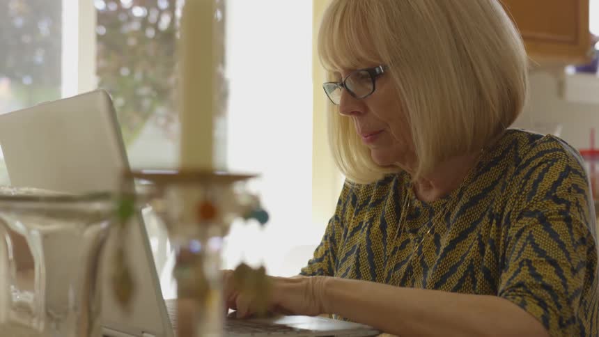 Woman typing on a laptop in her kitchen