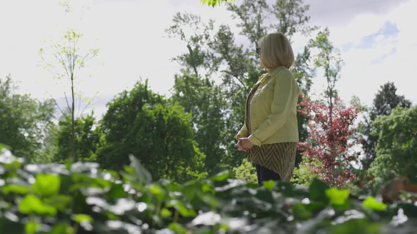 Woman is walking through garden on a sunny day