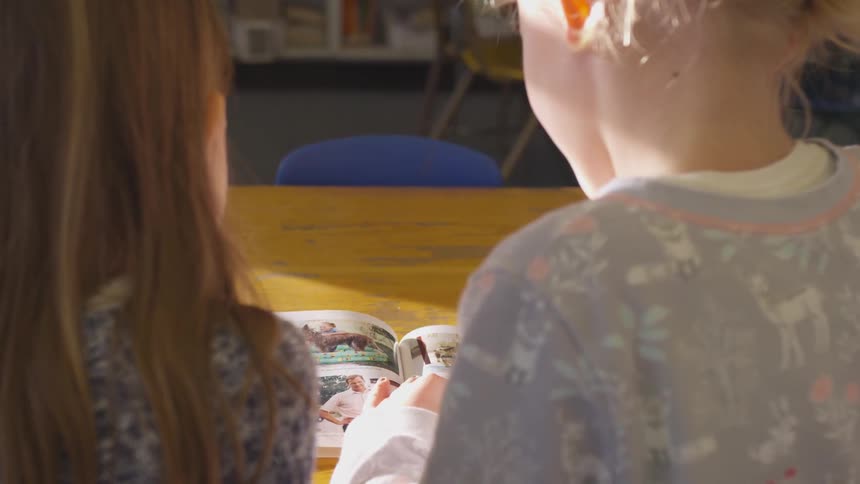 Two young girls look at picture book