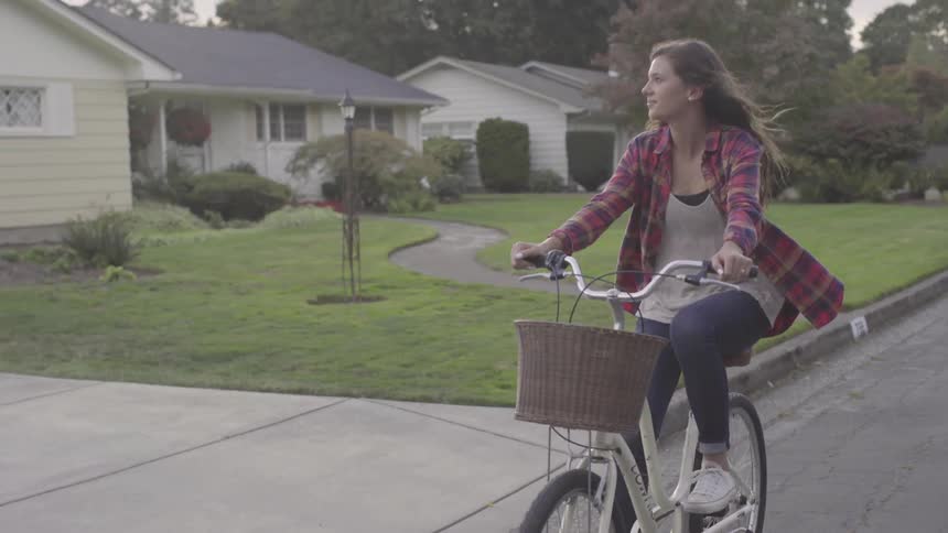 A woman rides a bike on a neighborhood road