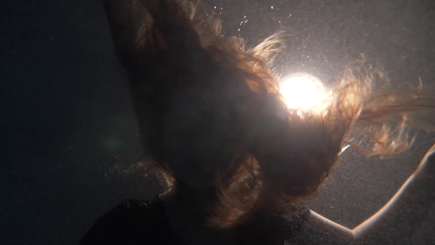 Slow motion of hair moving through the air in front of light