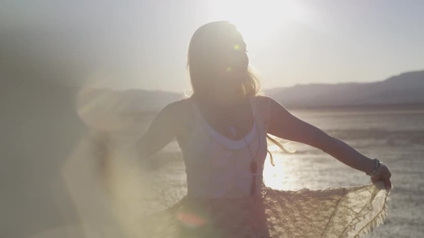 Woman walks near beach with sun glare