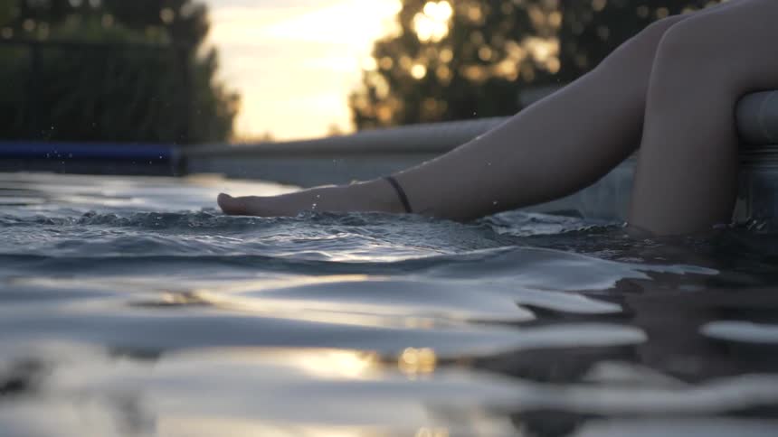 Feet kicking in water at edge of swimming pool