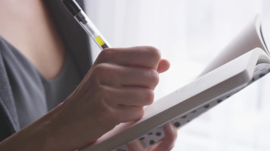 Woman's hand writing in notebook with pen